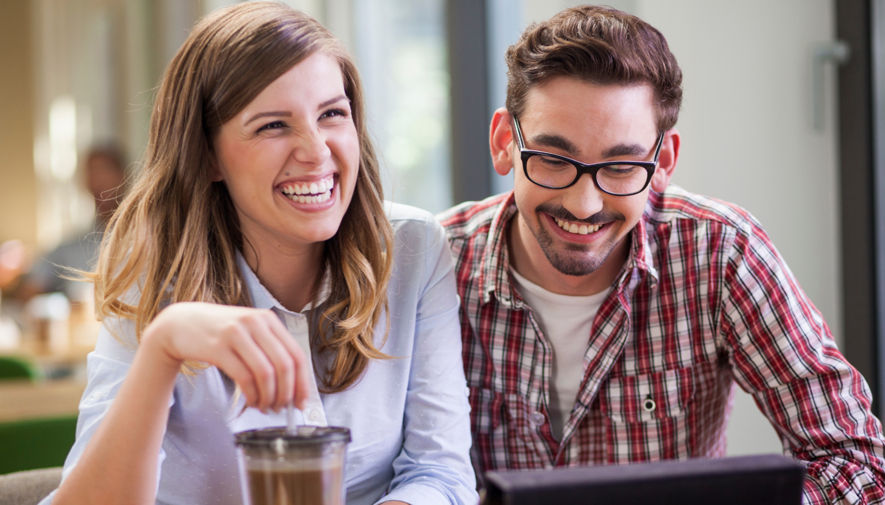 Une femme et un homme sourient devant un écran